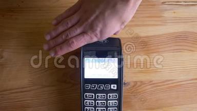 一个支付终端的特写镜头，用于支付手机上的应用程序在室内。 手按按钮